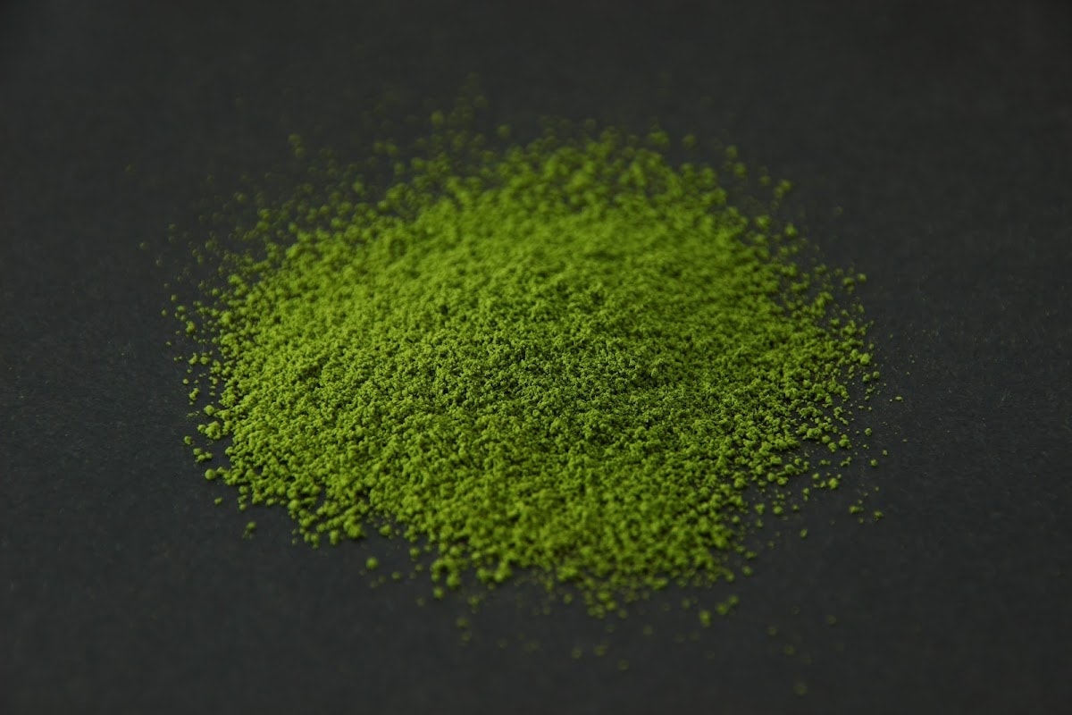 Bright green YMSC matcha powder heaped on a dark surface